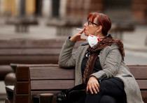 A woman smokes a cigarette as she sits on a bench in Liverpool