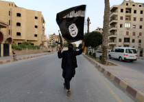 A member loyal to the Islamic State in Iraq and the Levant (ISIL) waves an ISIL flag in Raqqa June 2