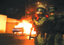 Esta es la imagen de la victoria de Hamás.  Los policías se paran cerca de un coche de policía en llamas durante los enfrentamientos con manifestantes árabes en la ciudad árabe-judía de Lod esta semana.