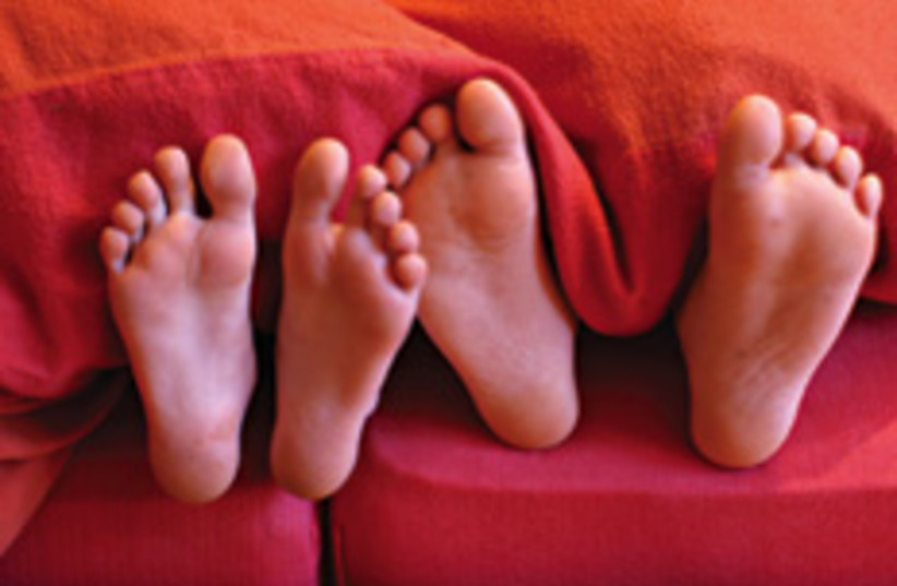 Two pairs of feet poke out from under a blanket (Illustrative) (photo credit: Courtesy)