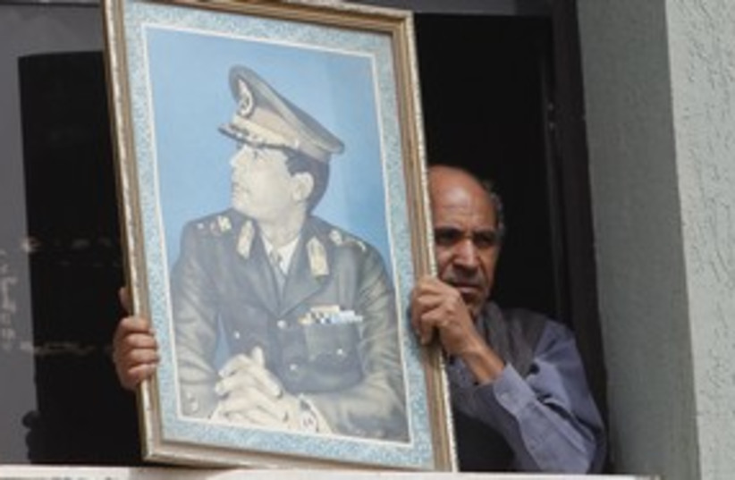 man holds pic of Gaddafi_311 (photo credit: Chris Helgren / Reuters)