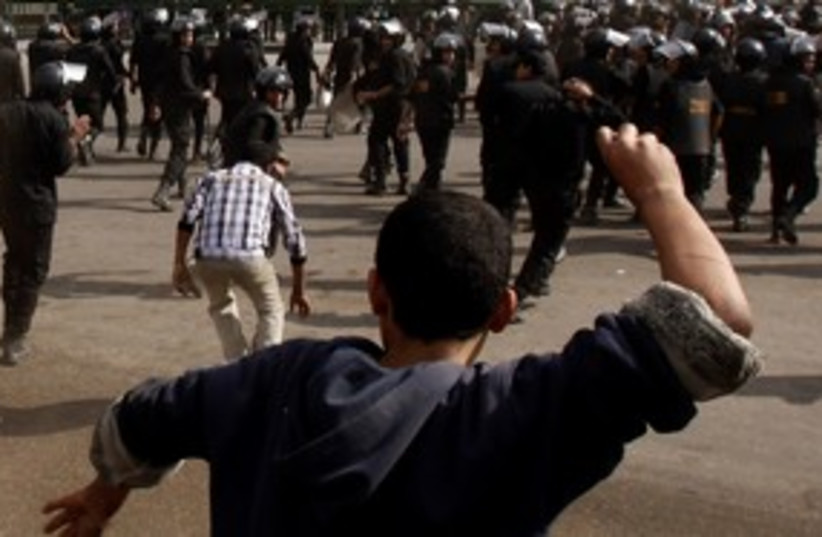 Protester throws rock at riot police in Tahrir Square 311 (photo credit: REUTERS)