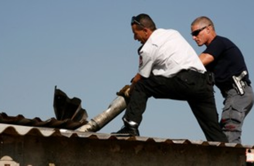 Israeli firefighter and policeman remove Katyusha rocket 311 (photo credit: REUTERS/Baz Ratner)
