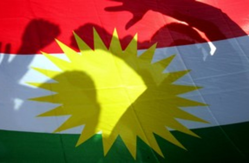 Kurds pose behind Kurdish flag_311 (photo credit: Mike Finn-Kelcey/Reuters)