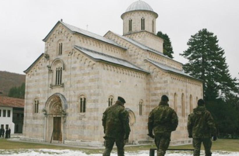 Kosovo Force soldiers walk pass a monastery in Decani 390 (photo credit: REUTERS)