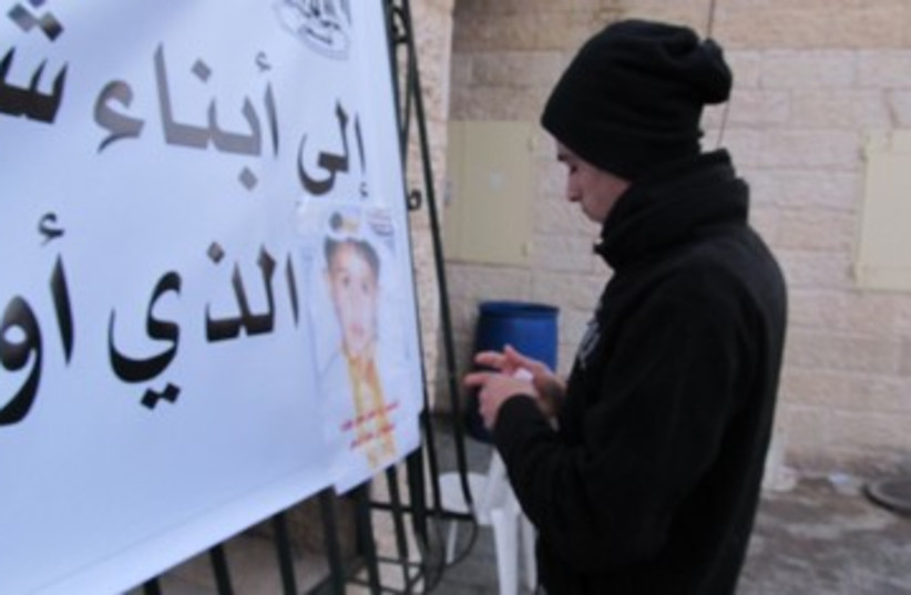 mourner hangs poster arabic bus accident 390 (photo credit: Melanie Lidman)