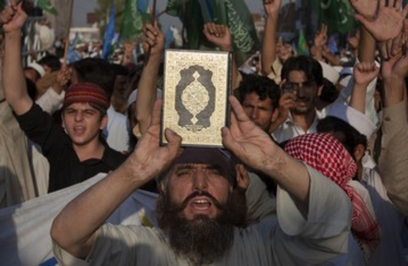 Protesters hold up Koran 390 (photo credit: REUTERS/Adrees Latif)