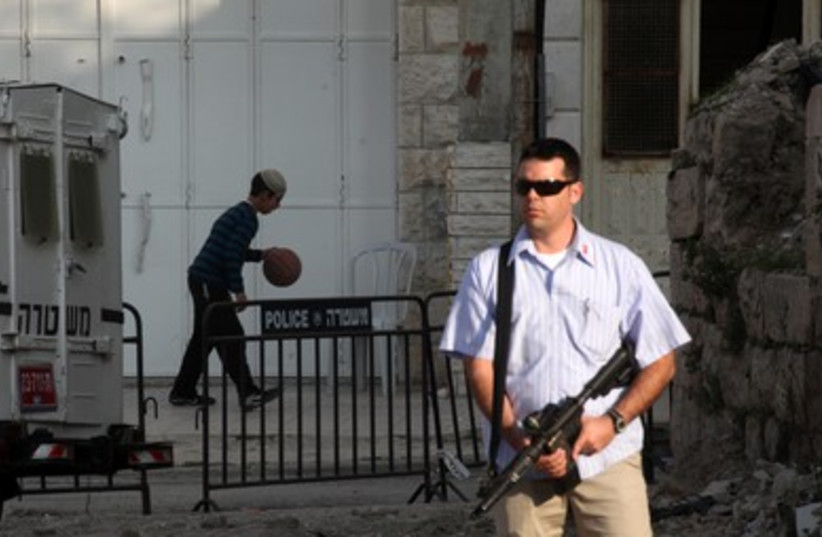 Armed guard stands by while settler plays ball