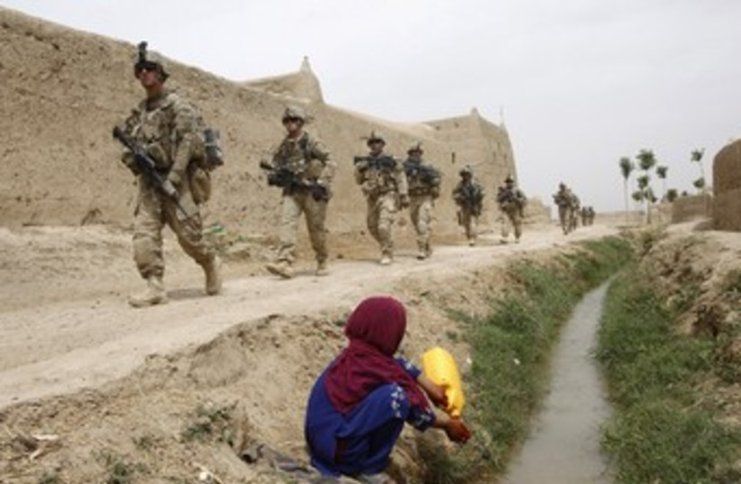 Afgan girl watches US soldiers walk past 370  (photo credit: REUTERS)