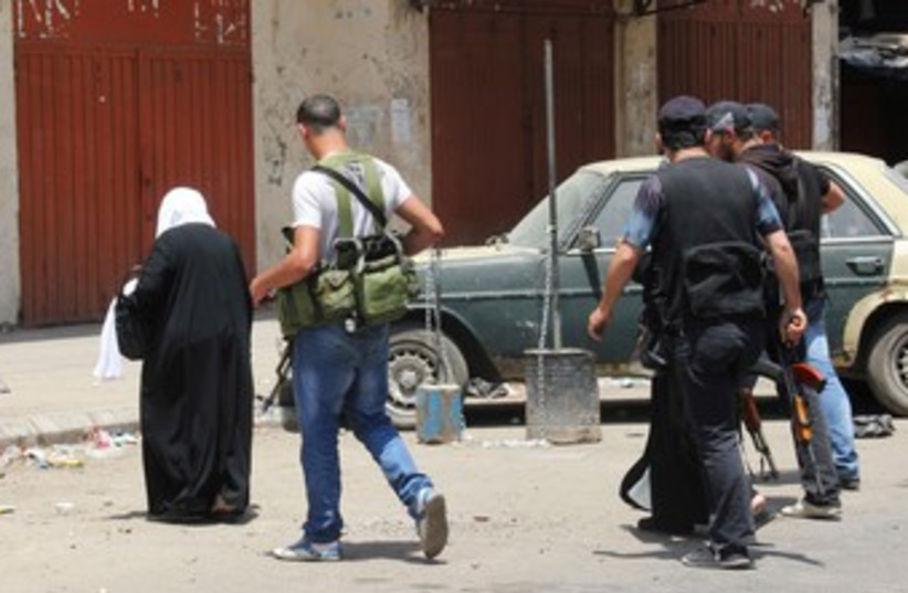 Woman walks past Sunni Muslim gunmen in Tripoli 370 (photo credit: REUTERS/Stringer)