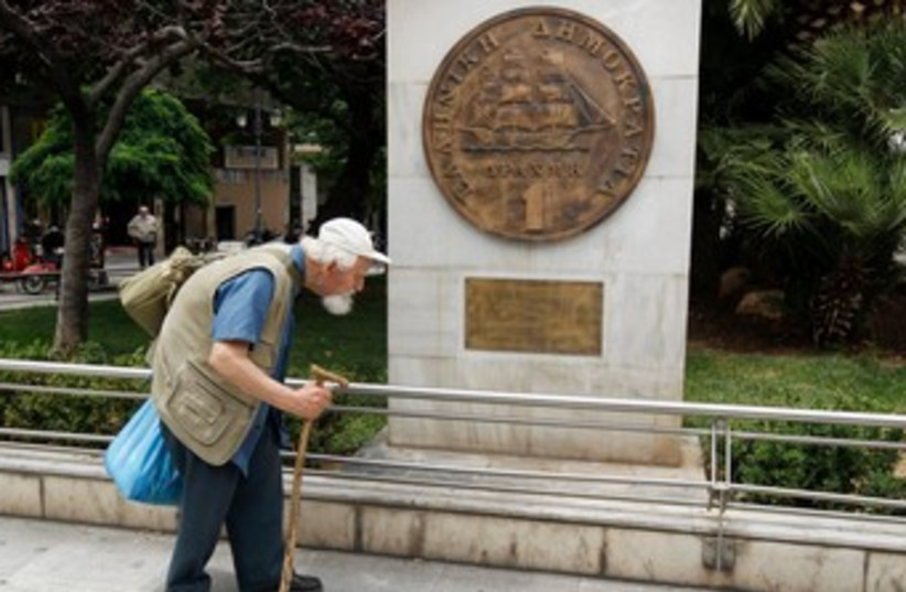 Greek man walks past drachma coin replica in Athens 370 (R) (photo credit: REUTERS/Yorgos Karahalis)