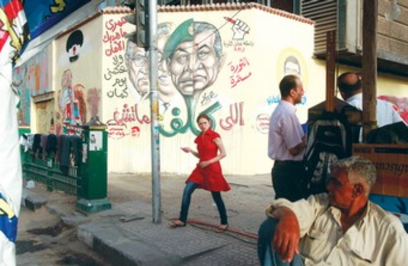 EGYPTIAN girl passes by graffiti 370 (photo credit: Asmaa Waguih/Reuters)