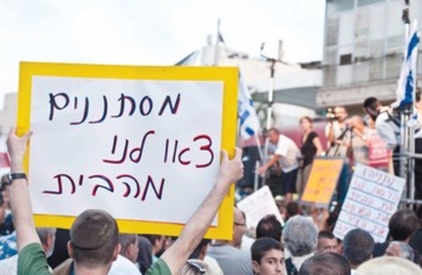 Man holding anti-migrant sign 370 (photo credit: Asaf Kliger/Israel Post)