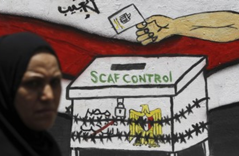 Egyptian walks past 'SCAF Control' graffiti 370 (R) (photo credit: Amr Dalsh / Reuters)