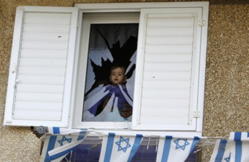 Baby in window of Netivot home damaged by Grad  (photo credit: REUTERS/Amir Cohen)