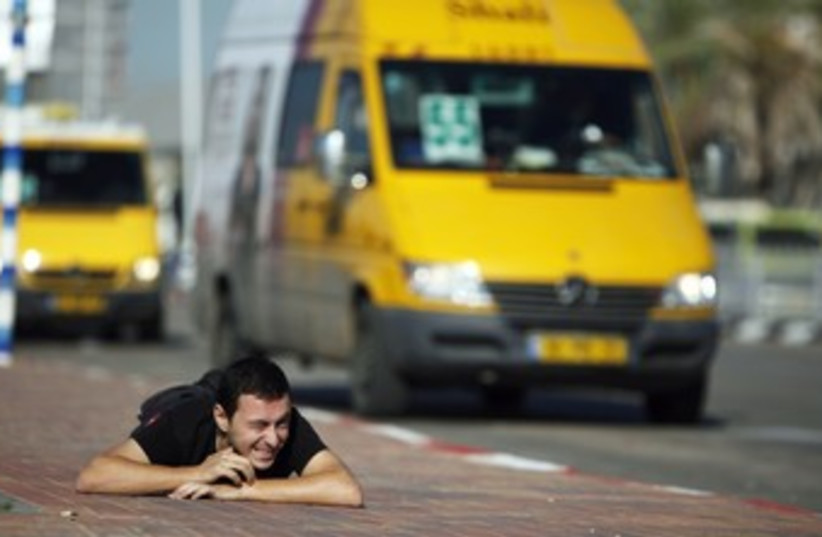Ashkelon man takes cover during code red siren 370 (photo credit: Reuters/Amir Cohen)