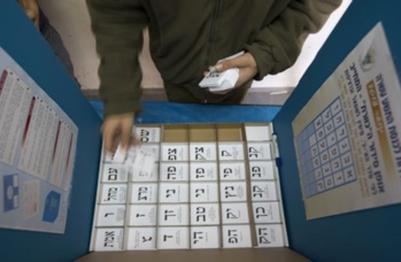An Israeli arranges ballots in a voting booth 370 (photo credit: Ronen Zvulun / Reuters)