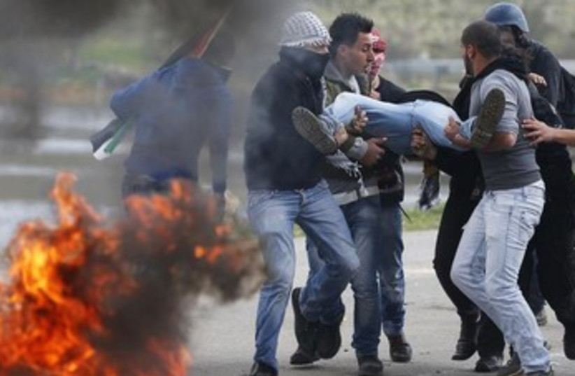 Palestinians carry protester injured by IDF (photo credit: REUTERS)