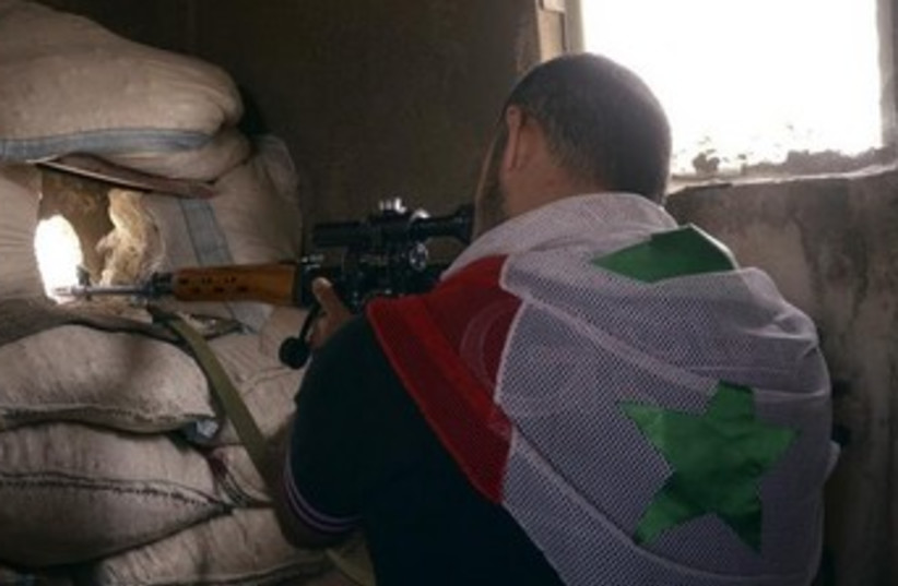 Syrian regime soldier with flag pointing gun (photo credit: REUTERS/George Ourfalian)