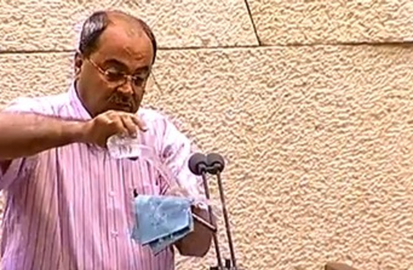 Ahmed Tibi pouring water on Prawer Bill 370 (photo credit: Courtesy of Knesset Channel)