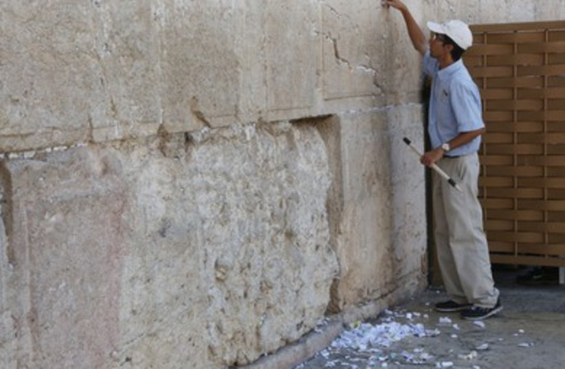 Workers at the Western Wall clean notes out of the crevices