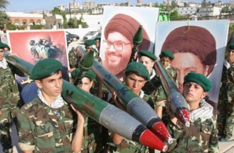 Hezbollah members carry mock rockets. (photo credit: REUTERS/Ali Hashisho)