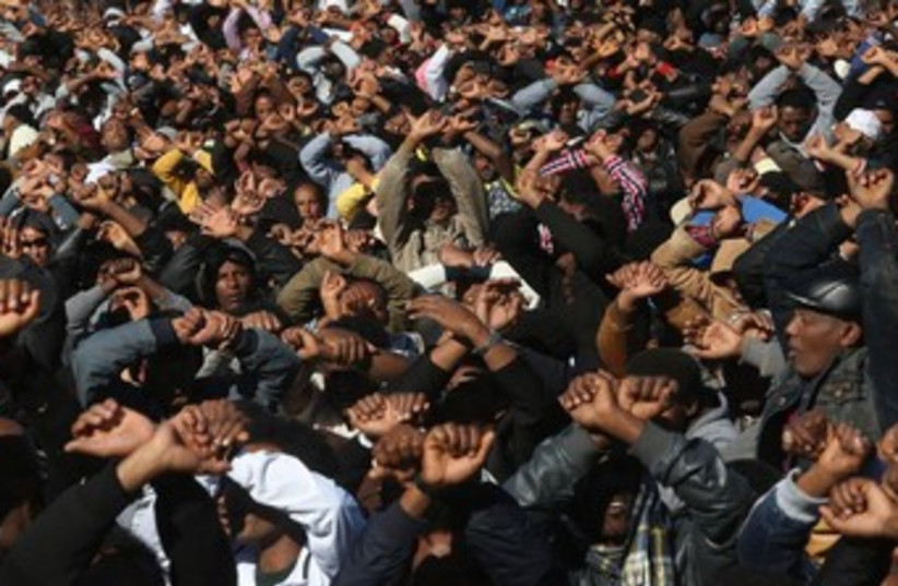 Migrants making hand gesture to signal imprisonment. (photo credit: Marc Israel Sellem/The Jerusalem Post))