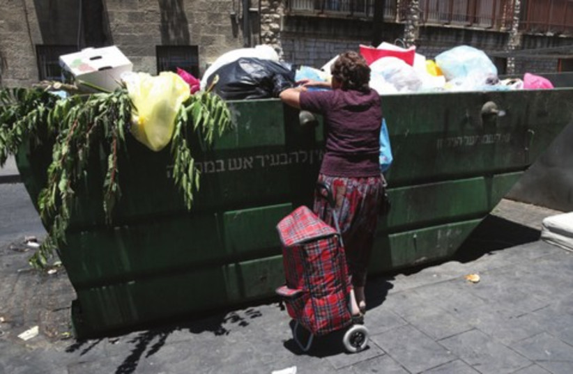 A woman searches through a garbage container in central Jerusalem (photo credit: NATI SHOHAT / FLASH 90)