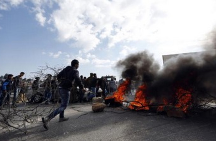 A Palestinian youth burn tires during a protest in the Jalazoun refugee camp, January 9, 2014. (photo credit: . REUTERS/Mohamad Torokman )