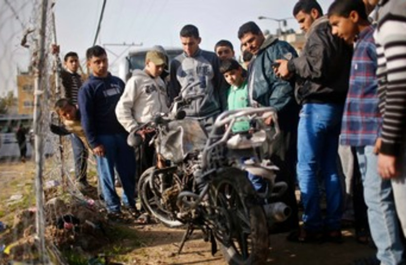 Palestinians look at a motorcycle, which witnesses said was hit in an Israeli air strike, in the northern Gaza Strip January 19, 2014. (photo credit: REUTERS)