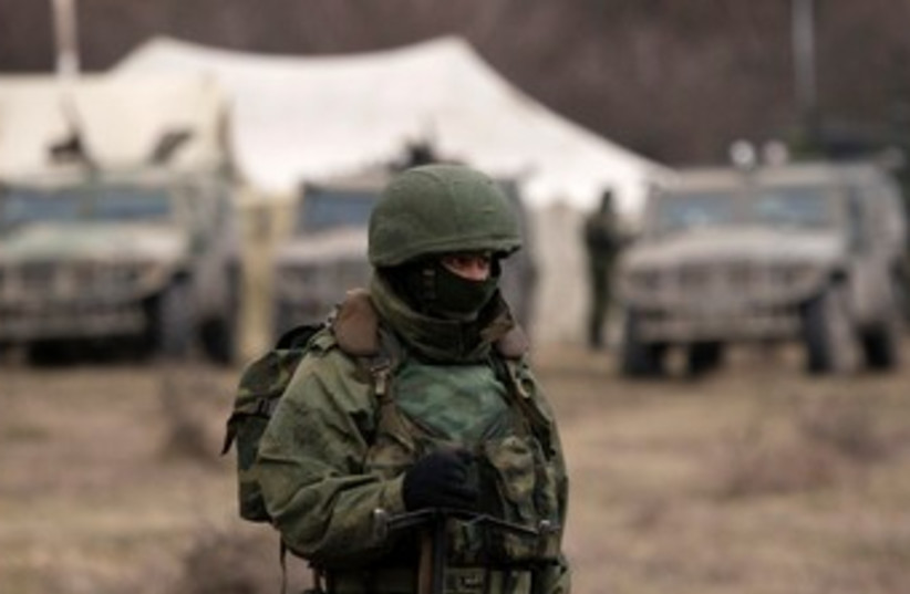 A military personnel member, believed to be a Russian serviceman, stands guard outside the territory of a Ukrainian military unit in the village of Perevalnoye outside Simferopol March 2, 2014.  (photo credit: REUTERS)