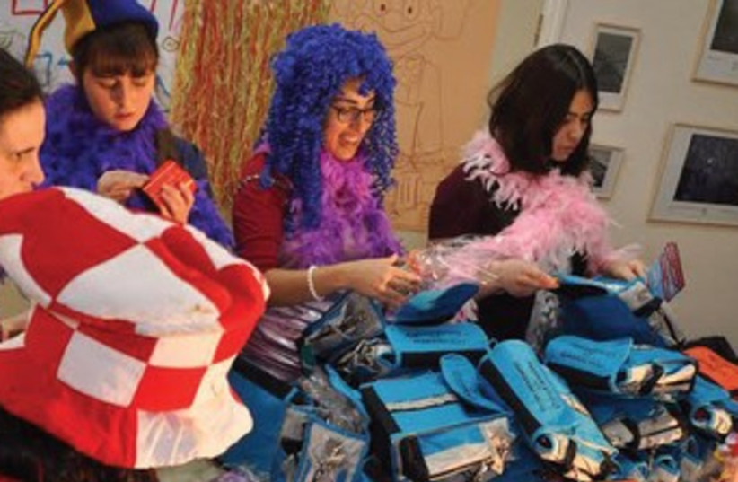 OneFamily staff bedecked in costumes prepare Purim baskets. (photo credit: SARAH LEVIN)