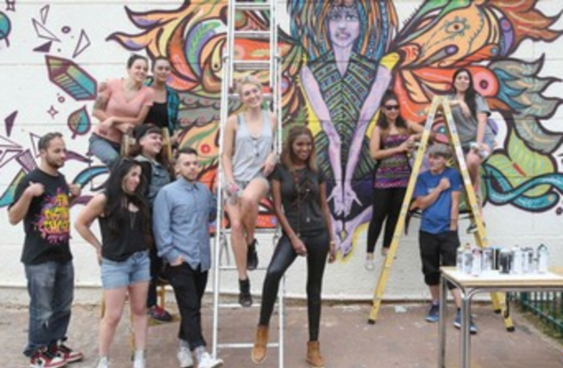 Titi Aynaw, former Miss Israel, joins in painting a wall. (photo credit: NIMROD GLIKMAN)