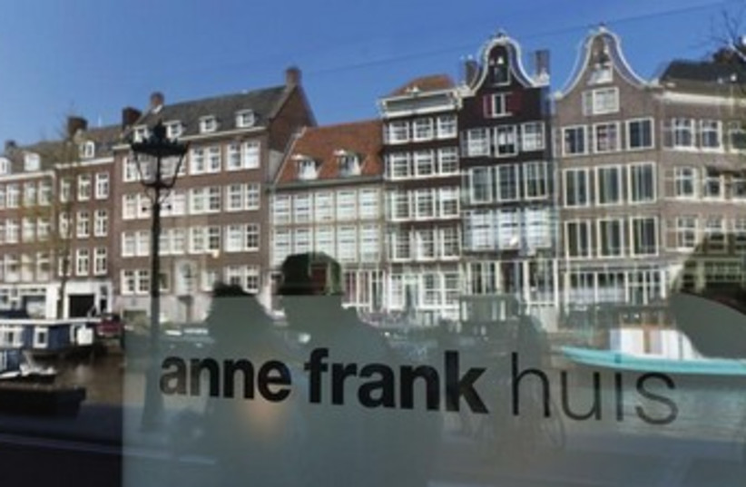 Reflections of tourists and canal houses seen in the window of the Anne Frank museum in Amsterdam. (photo credit: REUTERS)