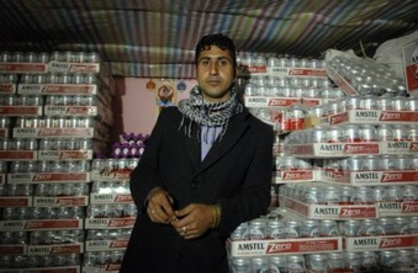 A smuggler poses with cartons of beer during an alcohol smuggling operation to Iran (photo credit: REUTERS)