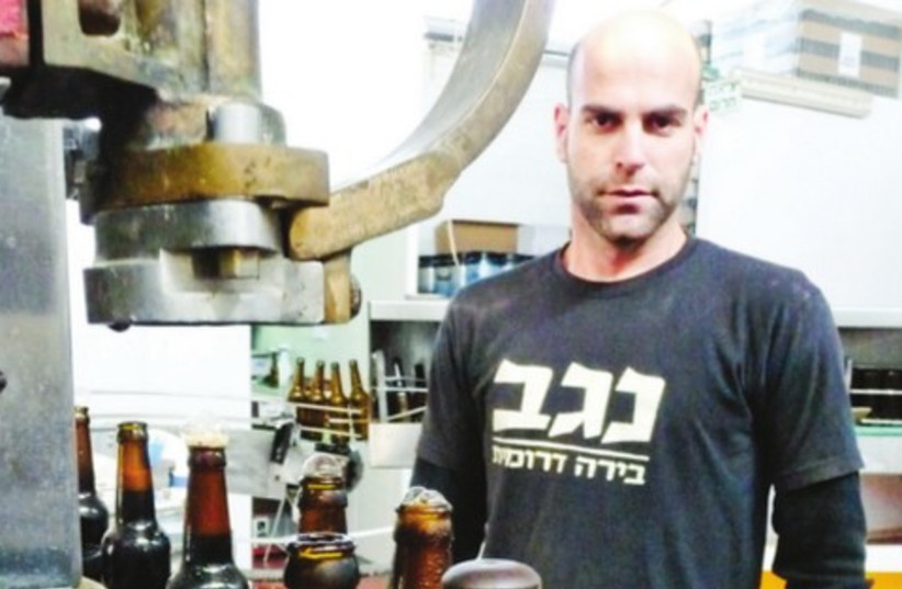CEO SAGIV Karlboim stands near the bottle assembly line in the Kiryat Gat brewery of Negev Beer (photo credit: Courtesy)
