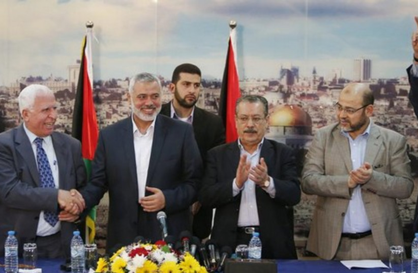 Senior Fatah official Azzam Al-Ahmed (L), shakes hands with head of the Hamas government Ismail Haniyeh after announcing a reconciliation agreement in Gaza City April 23, 2014. (photo credit: REUTERS)