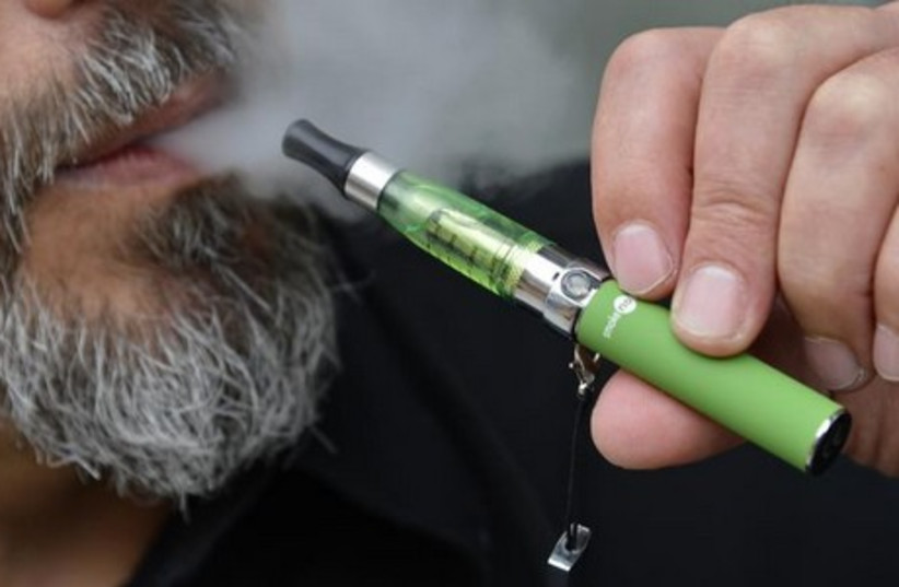 Gabor Kovacs of '-smoke no smoke' puffs on an electronic cigarette that his shop sells at Camden in London June 9, 2013.  (photo credit: REUTERS)