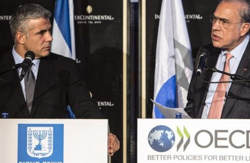 Jose Angel Gurria (R), Secretary-General of the Organization for Economic Cooperation and Development (OECD), at a news conference with Finance Minister Yair Lapid. (photo credit: REUTERS)