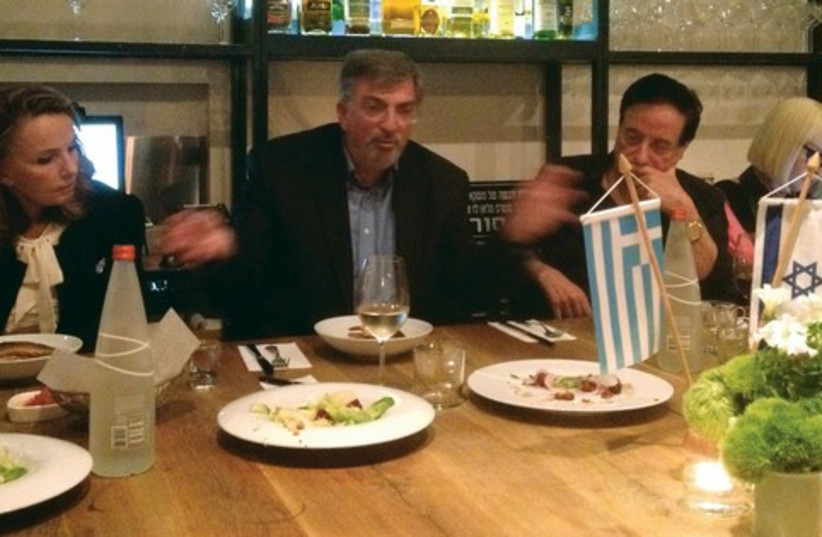 Greek Ambassador Spiros Lampridis (second from left) speaks to dinner attendees, before a centerpiece of Greek/Israeli flags (photo credit: SETH J. FRANTZMAN)