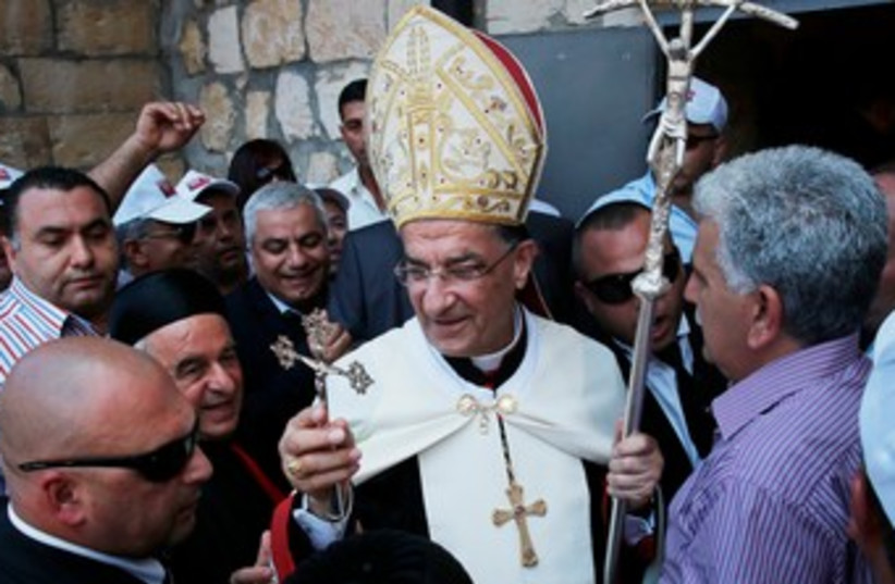 Maronite Patriarch Beshara al-Rai (C) holds a cross during his visit to Birim, a northern Israeli village, May 28, 2013 (photo credit: REUTERS)