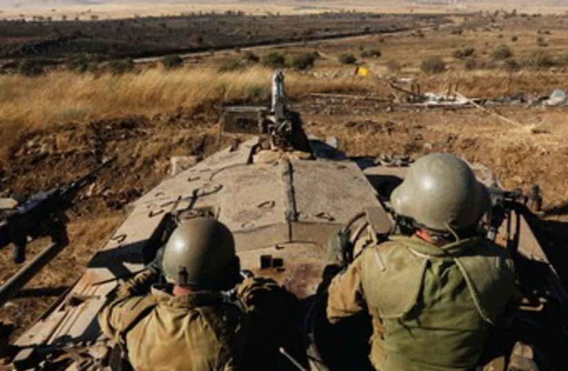 SOLDIERS SIT atop a tank as they watch the border with Syria near Quneitra (photo credit: REUTERS)