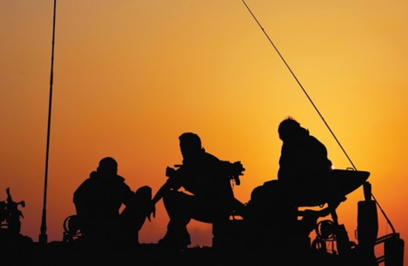 Soldiers site on their vehicle as the sun sets over the Negev. (photo credit: REUTERS)