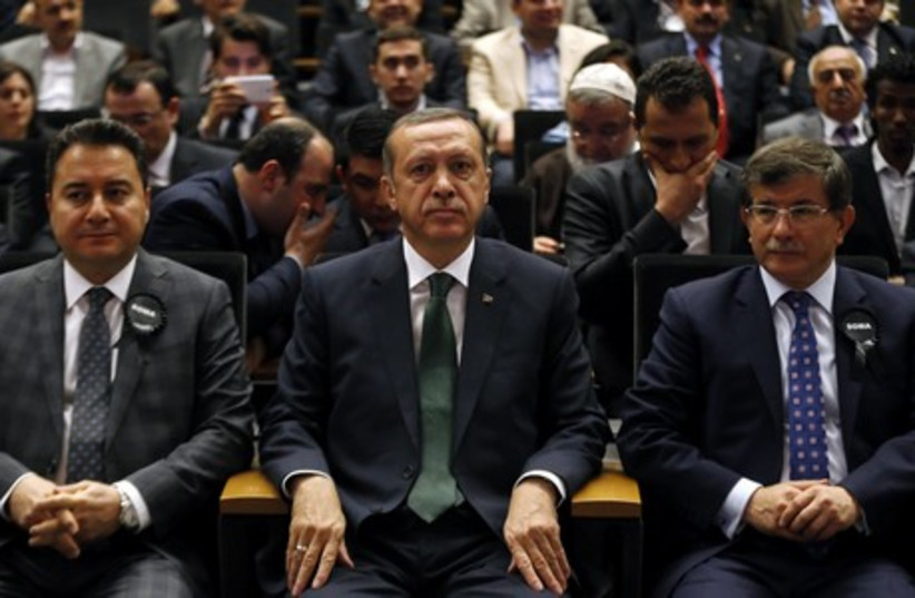 Turkey's Prime Minister Tayyip Erdogan, flanked by Deputy Prime Minister Ali Babacan (L) and Foreign Minister Ahmet Davutoglu (R), attends a meeting in Ankara in this May 19, 2014 file photo.  (photo credit: REUTERS)