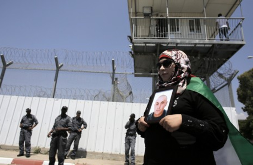 A Palestinian woman holds a picture of a Palestinian jailed in an Israeli prison during a protest in Ramle (photo credit: REUTERS)