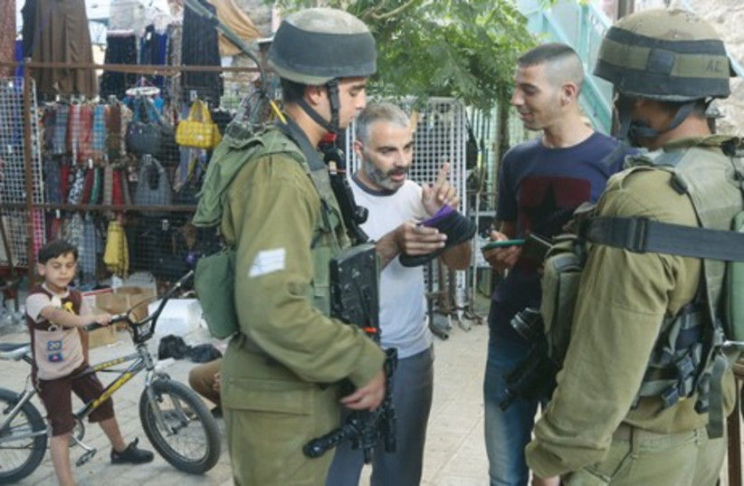 IDF soldiers speak with Palestinians in Hebron last week during the manhunt for three kidnapped Israeli youth. (photo credit: MARC ISRAEL SELLEM/THE JERUSALEM POST)
