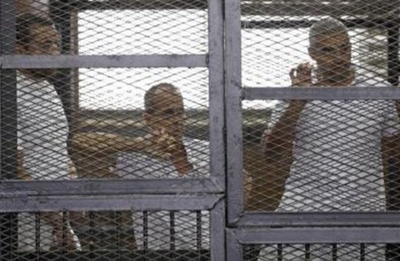 Al Jazeera journalists (L-R) Peter Greste, Mohammed Fahmy and Baher Mohamed stand behind bars at a court in Cairo June 1, 2014. (photo credit: REUTERS)