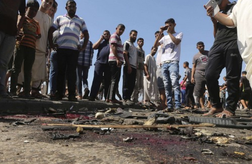 Palestinians survey the wreckage of an IAF strike that killed two terrorists in Gaza. (photo credit: REUTERS)