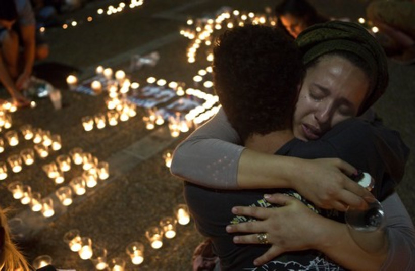 Israeli women hug each other as people light candles in Tel Aviv's Rabin Square as they mourn the death of three teenagers who were abducted, June 30, 2014.  (photo credit: REUTERS)