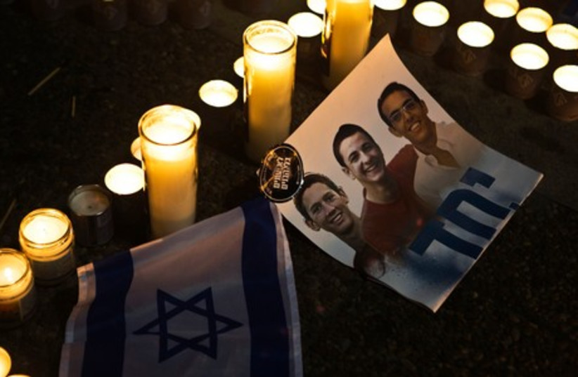 Candles placed next to a picture of three Israeli teenagers who were abducted and killed, in Tel Aviv's Rabin Square June 30, 2014. (photo credit: REUTERS)